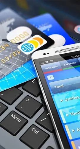 A smartphone displaying a banking app lies on a laptop keyboard next to several credit cards.