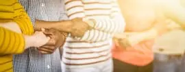 A group of individuals are standing close together, clasping each other's hands in a show of unity or agreement.