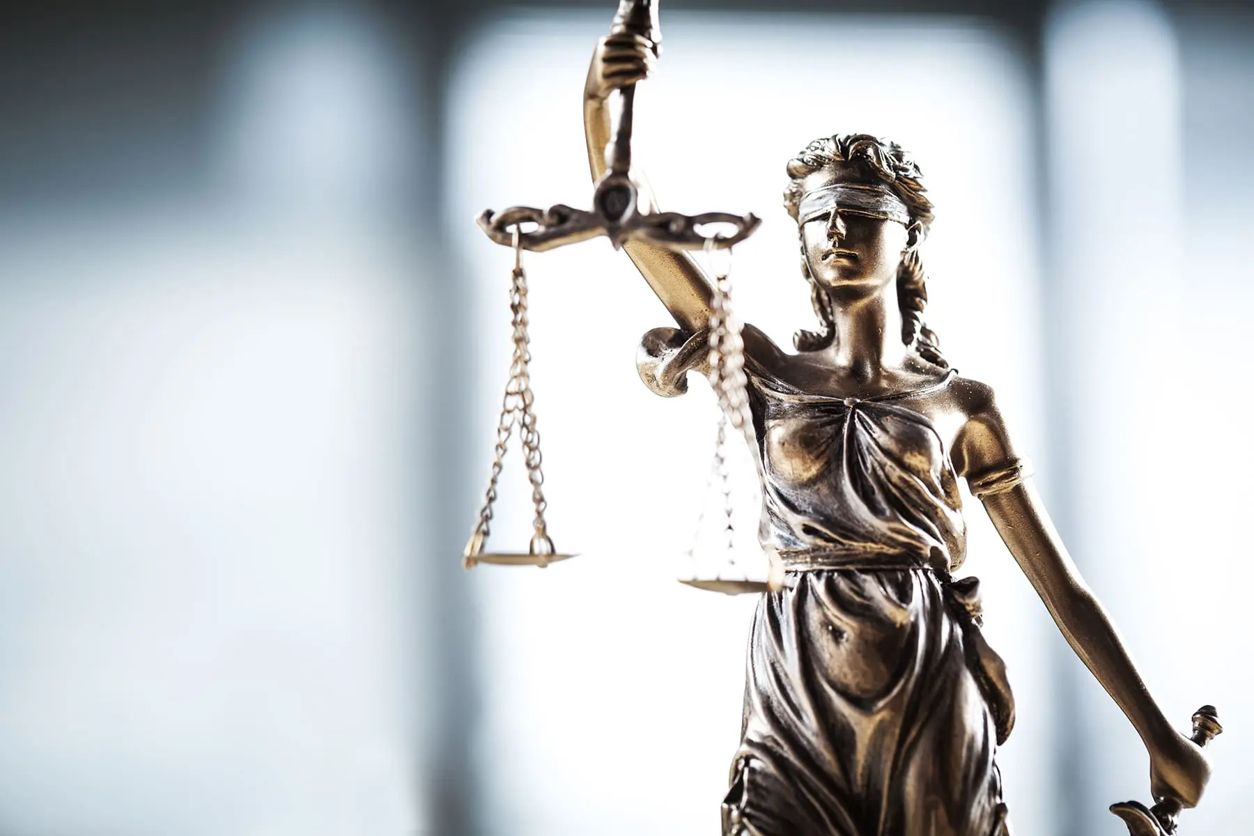 A statue of Lady Justice, blindfolded and holding a sword and scales, symbolizes the fair and equal administration of the law without corruption, avarice, prejudice, or favor.