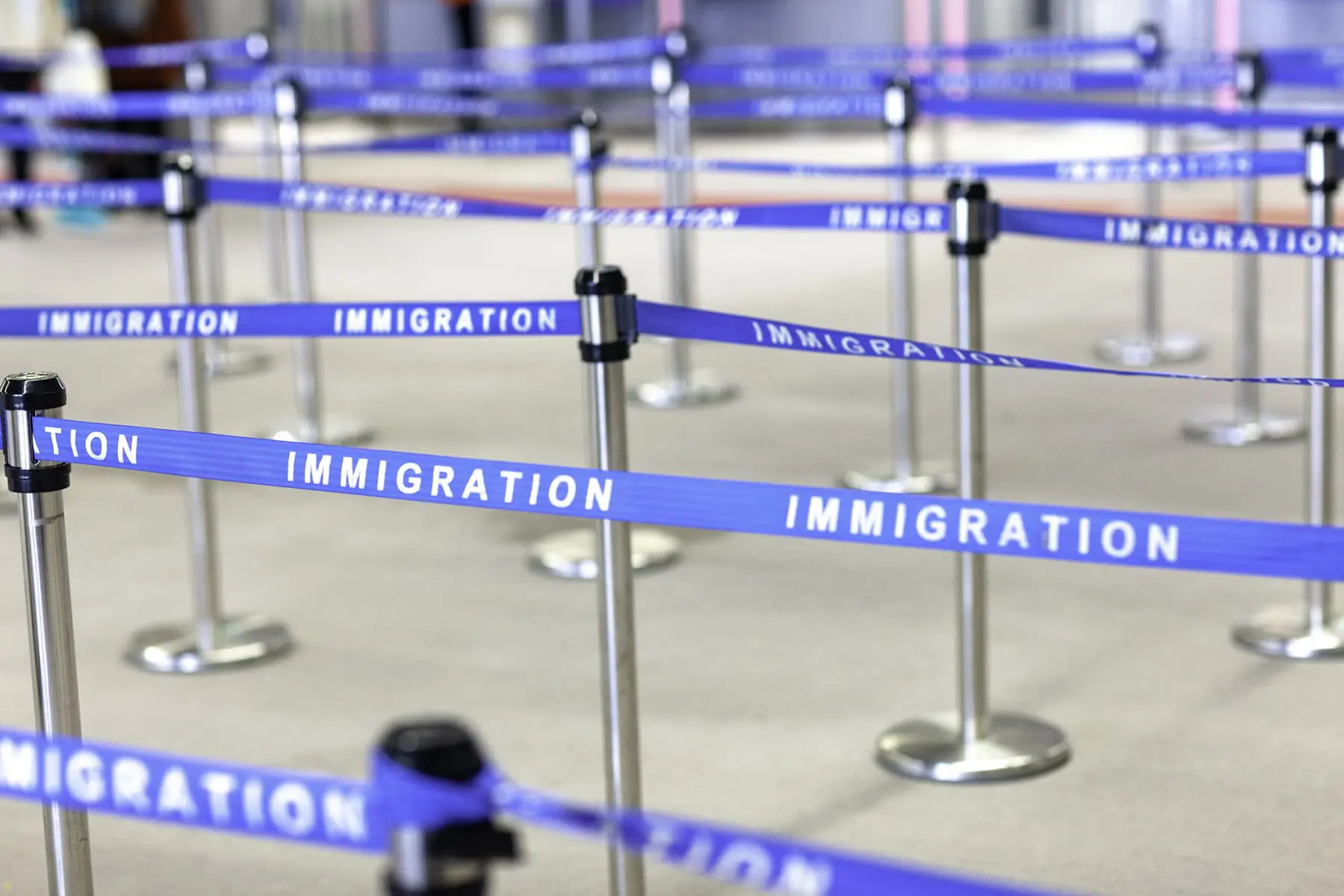 Blue "Immigration" barriers create a queue system with metal posts.