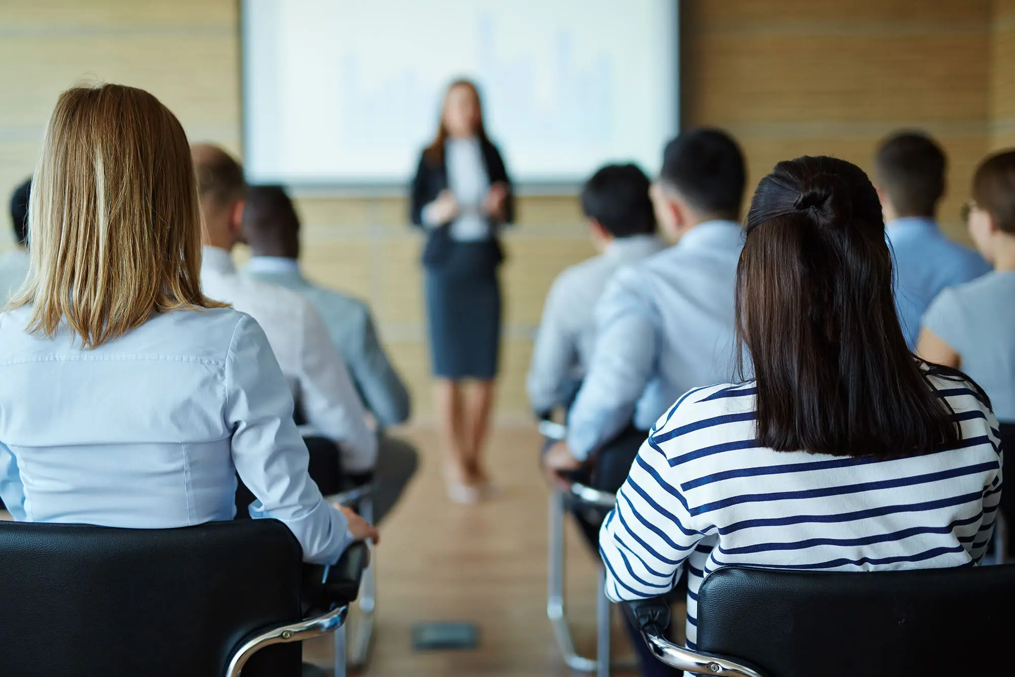 A professional speaker is giving a presentation to an attentive audience in a conference room.