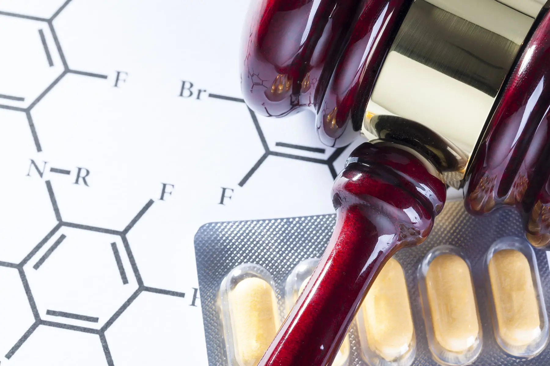 Gavel next to pills and chemical chart