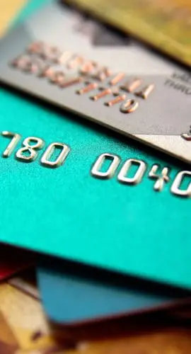 A stack of colorful credit cards is spread out, displaying some of the card numbers.
