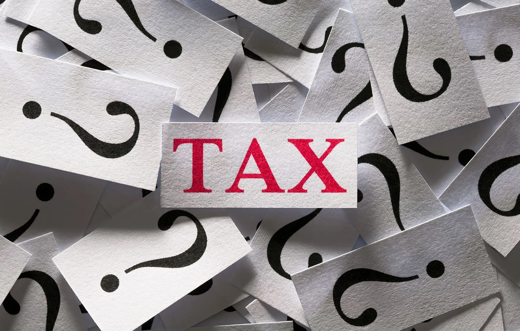 A red "TAX" is surrounded by multiple white cards with black question marks on them.