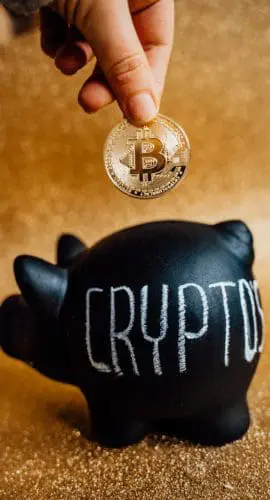Person putting bitcoin in a piggy bank