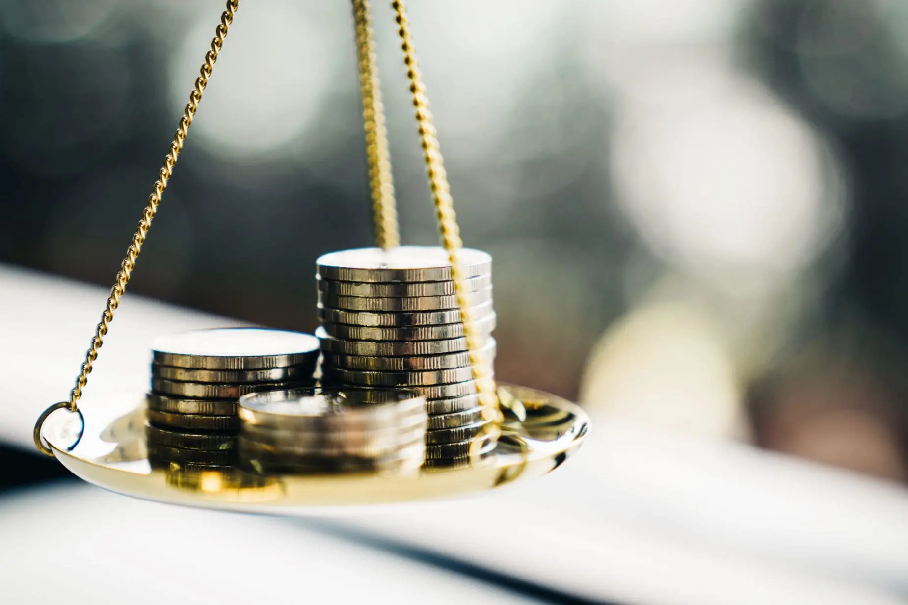 A balance scale is holding stacks of coins.