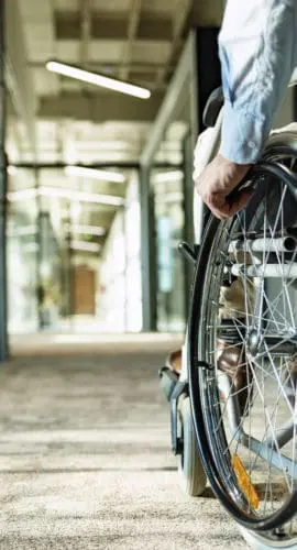 Paralyzed man in a wheelchair on the move in the disabled office building.