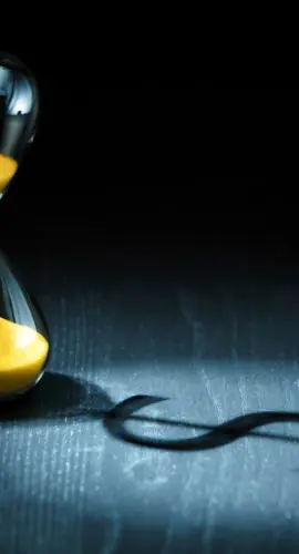 Hourglass projecting a dollar sign as shadow.